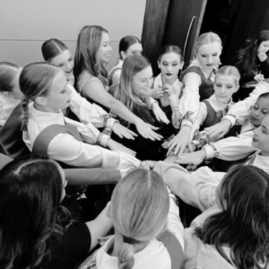 Dancers forming a circle with hands joined in unity and anticipation before stepping onto the competition stage.
