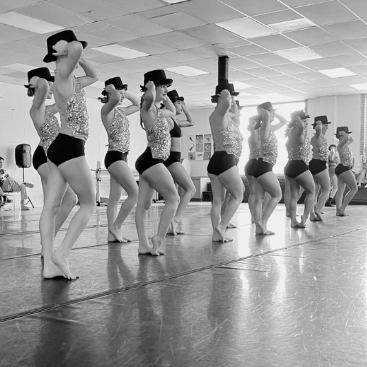 Talented dancers lined up at Charleston Dance Center, practicing a spirited Broadway routine.