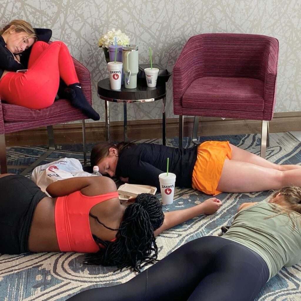 four dancers sleeping on the convention center floor and chairs during their lunch break from dance classes.